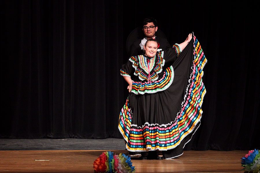 Alumnus Nathaniel Pierce stands behind alumna Hailey Bishop as she displays her traditional folklorico dress.