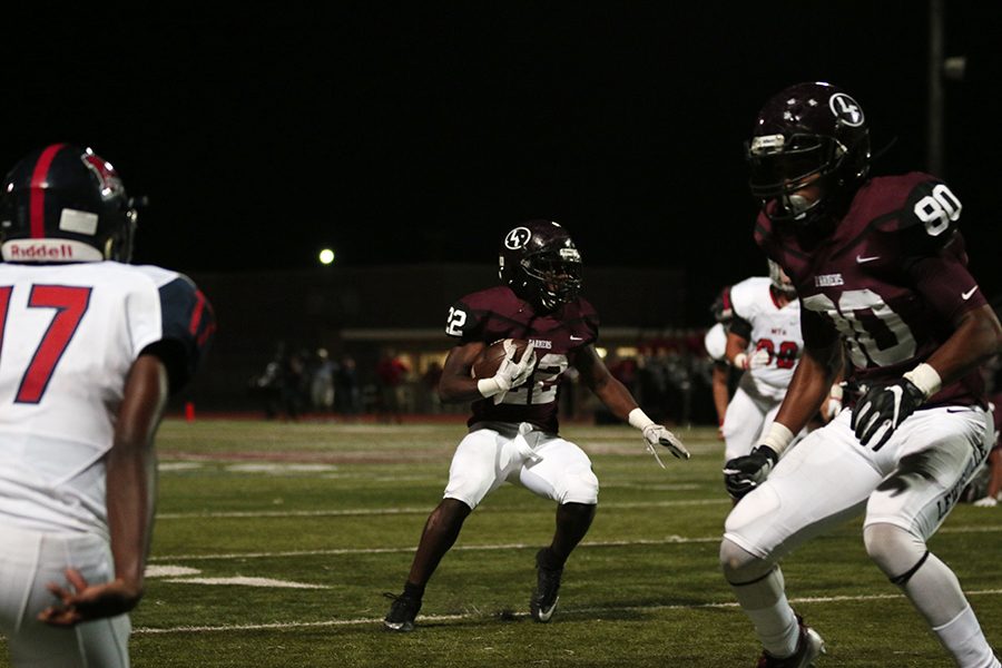 Senior defensive lineman Emmanuel Adesina (90) gets ready to block a McKinney Boyd player in order for senior Kwame Mickels (22) to run the ball.