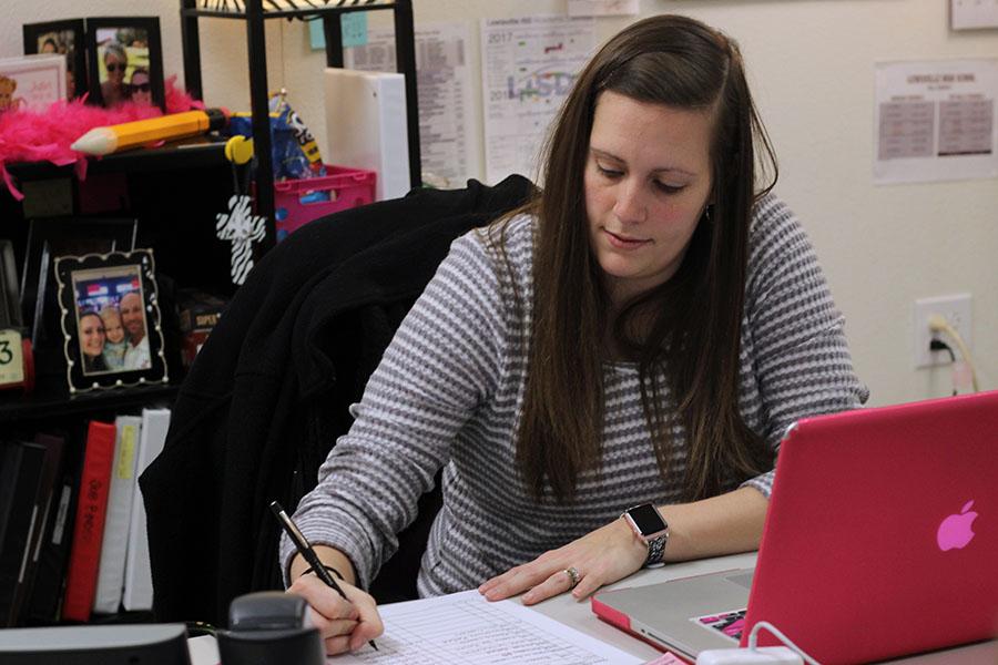 Teacher Amy Payne works on classwork with students about expenses.