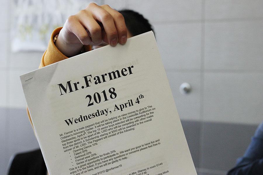 A student holds up information for the upcoming male pageant.