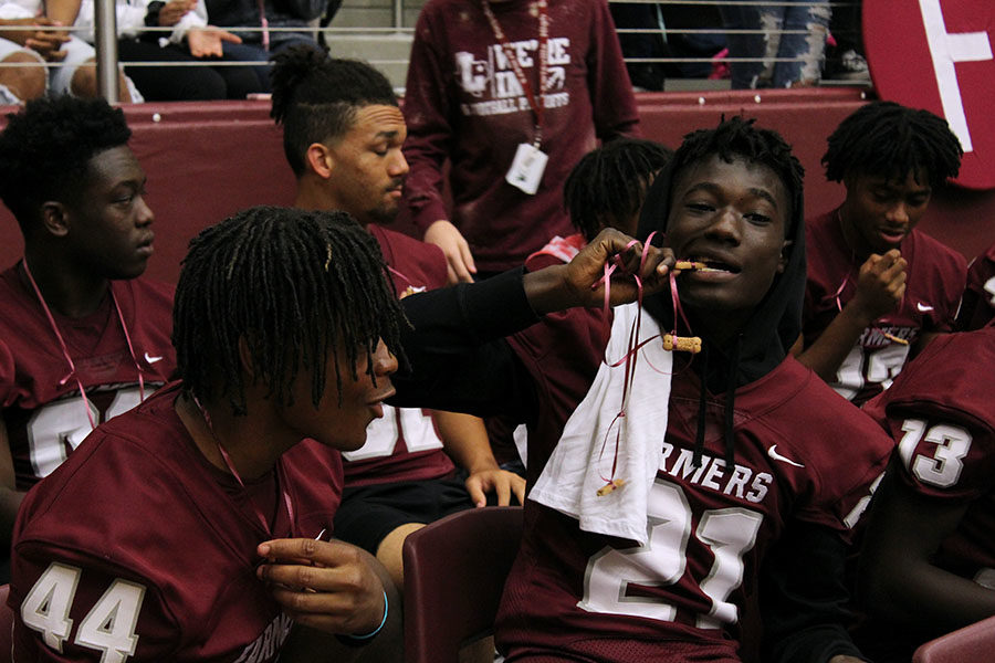 Senior Shadwel Nkuba (21) eats a dog treat made for the football players by StuCo.