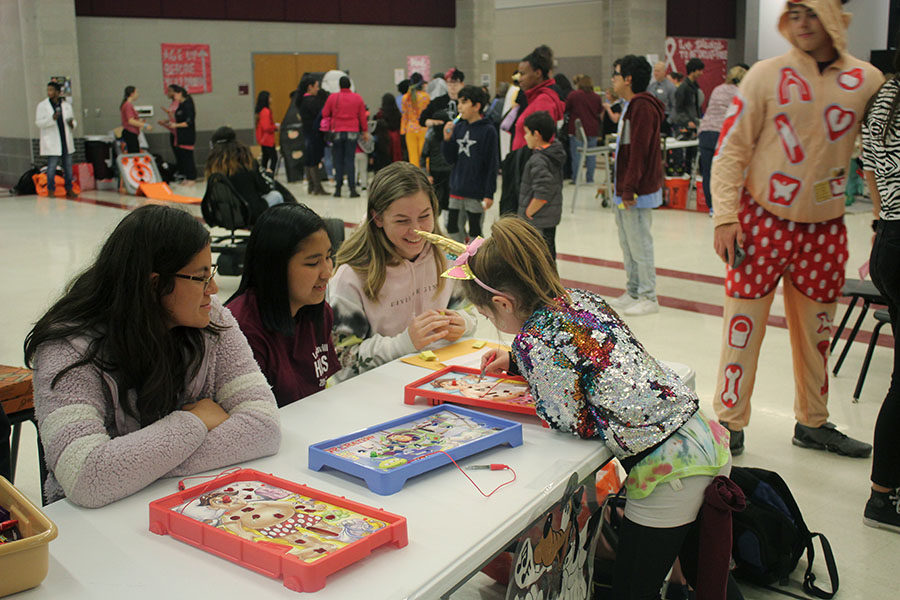 Student volunteers senior Monica Acosta, junior V Tra and senior Claire Fowler help procter the Operation game booth.